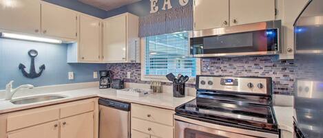 A modern kitchen with white cabinets, a stainless steel oven, and a microwave.