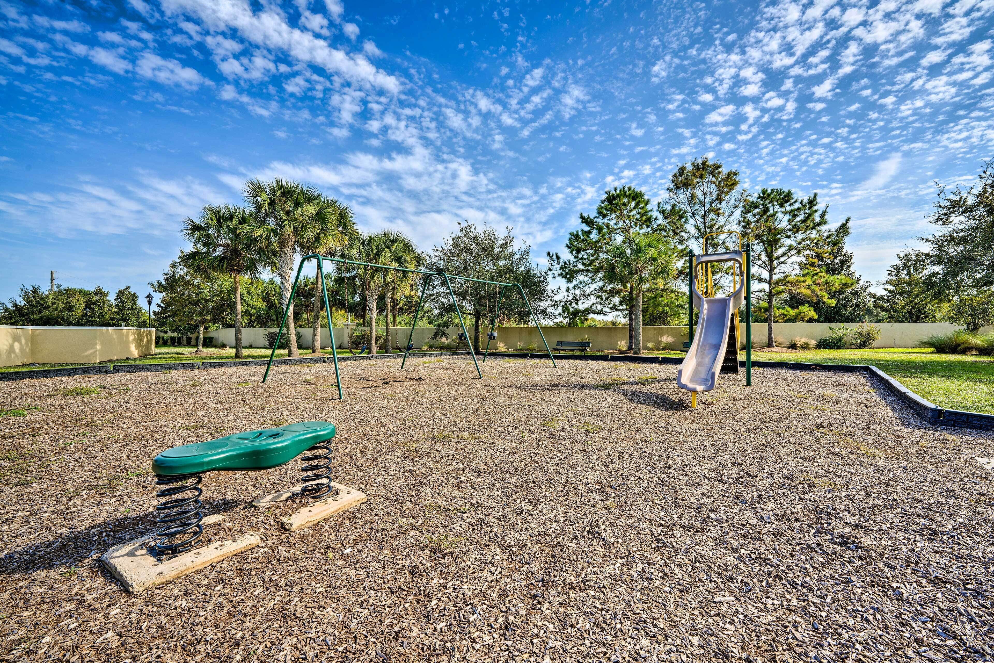 A playground with a swing set, a slide, and a spring-mounted bench.
