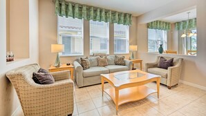 A living room with a beige sofa, two armchairs, a coffee table, and a dining table. There are two windows with blinds and a ceiling fan. - Kissimmee Getaway ~ 4 Mi to Walt Disney World (Kissimmee)
