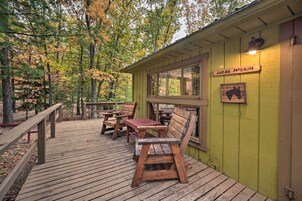 Una terraza de madera con mesas de picnic y bancos, un edificio verde con una ventana, y un letrero que dice "Lucas McCain".