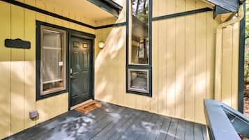A wooden porch with a dark door, a small window, and a welcome mat.