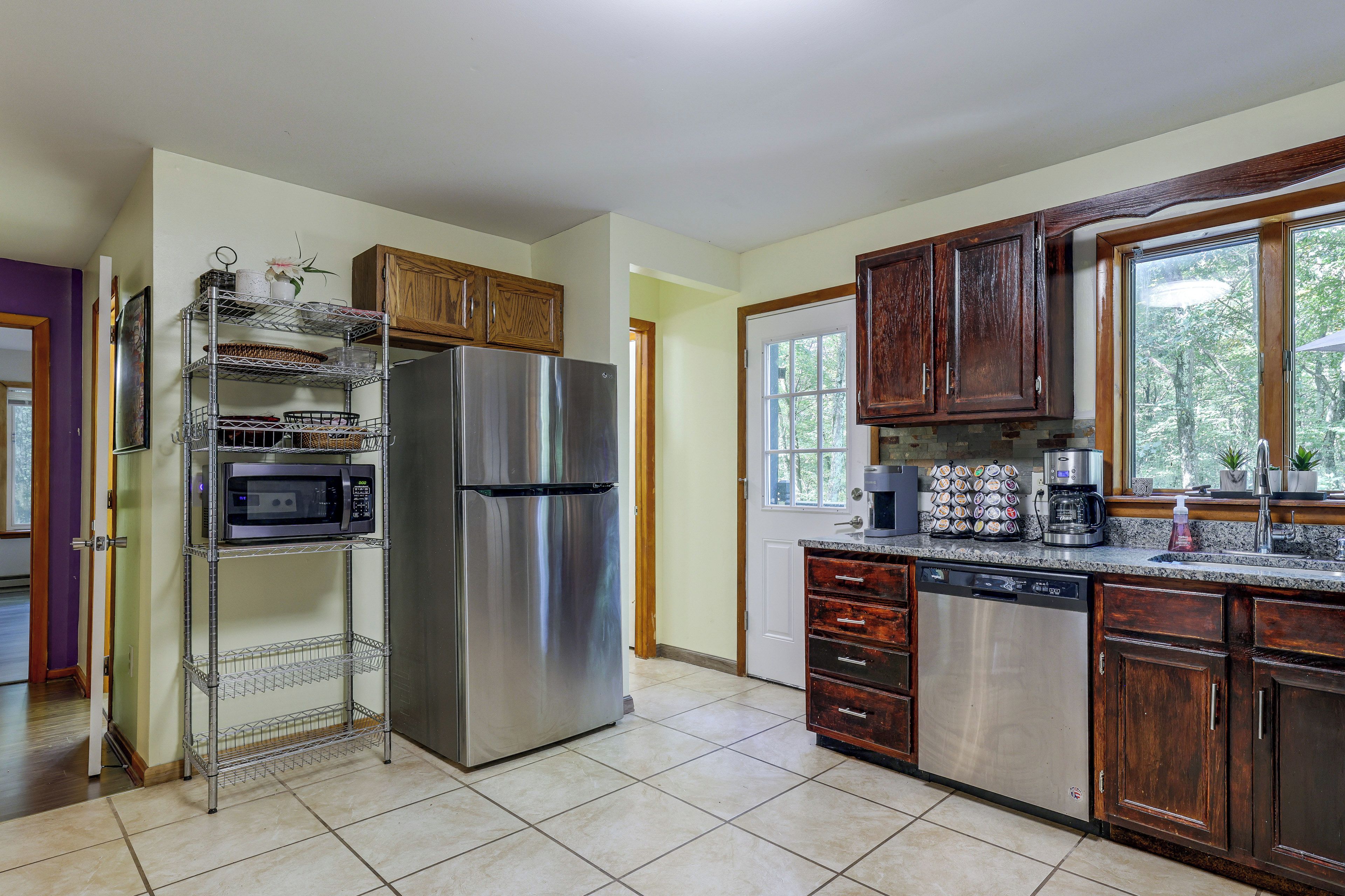 A kitchen with stainless steel appliances, wooden cabinets, and a tiled floor.