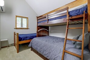 Une chambre avec un lit superposé, une fenêtre, un radiateur et une armoire en bois.
