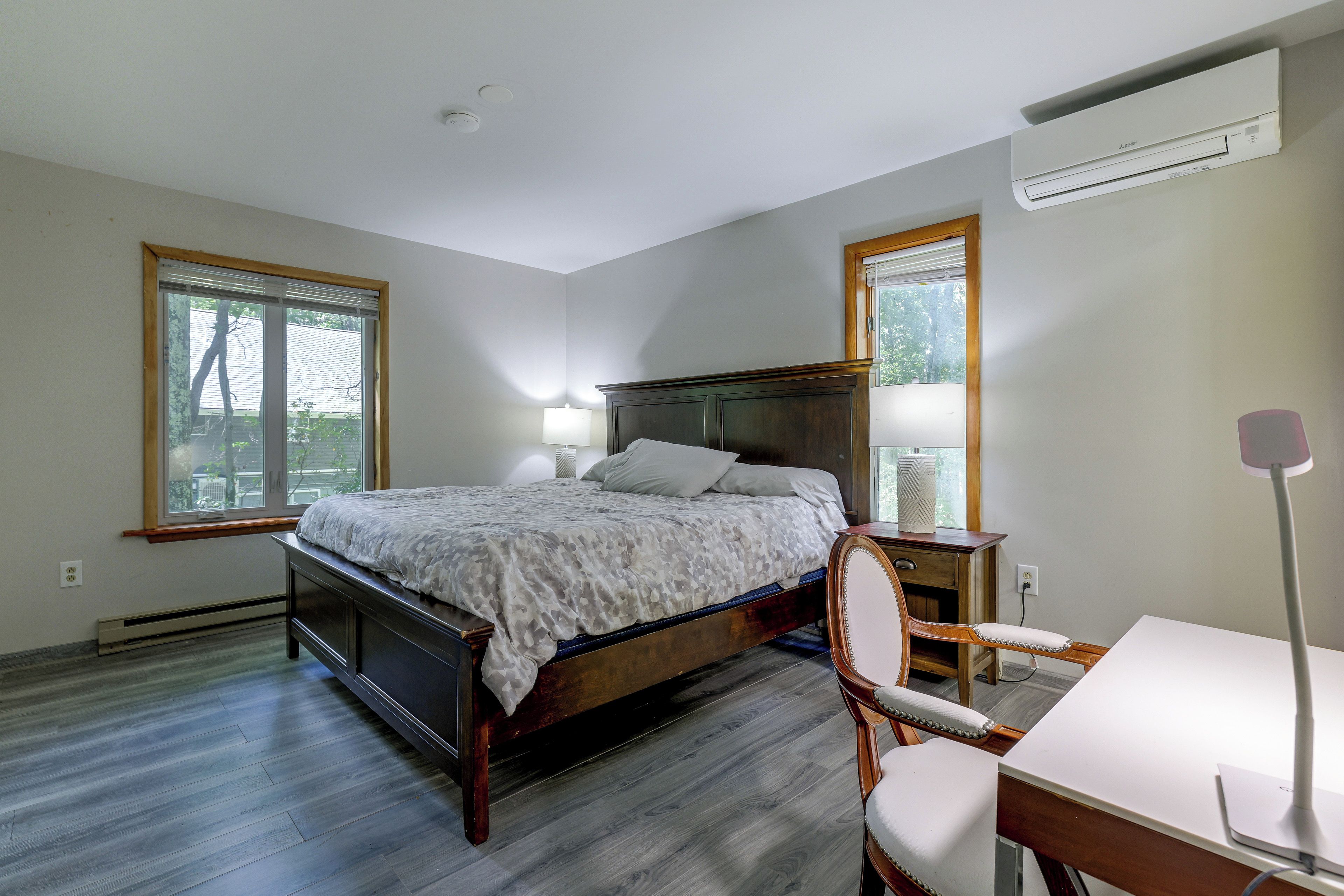 A bedroom with a bed, bedside tables, a desk, and a chair.