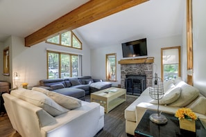 Un salón amplio con chimenea, ventanas grandes y un techo alto con vigas a la vista.