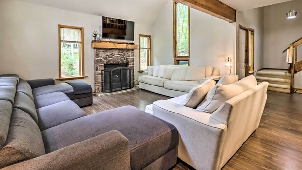 Una sala de estar amplia con un sofá modular, un sofá blanco y una chimenea de piedra.