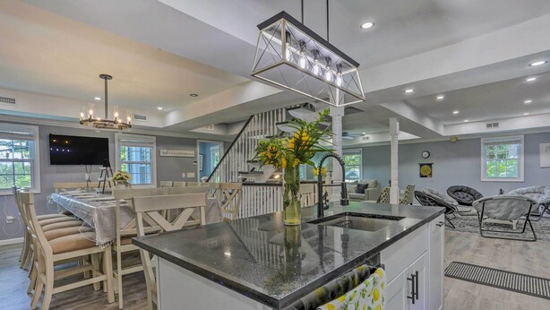 A spacious kitchen with a central island, dining area with chairs, and a staircase leading to another level. - Stunning South Fallsburg Home w/ Pool & Deck! (South Fallsburg)