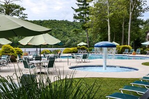 A pool area with lounge chairs and umbrellas, surrounded by greenery and trees. - 1 Mi to Big Boulder: Lakefront Unit w/ Pool Access (Lake Harmony)