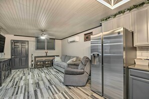 A modern kitchen with a stainless steel refrigerator, a grey sofa, and a patterned floor.