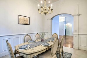 Comedor con una mesa grande, sillas, una araña y un cuadro en la pared.