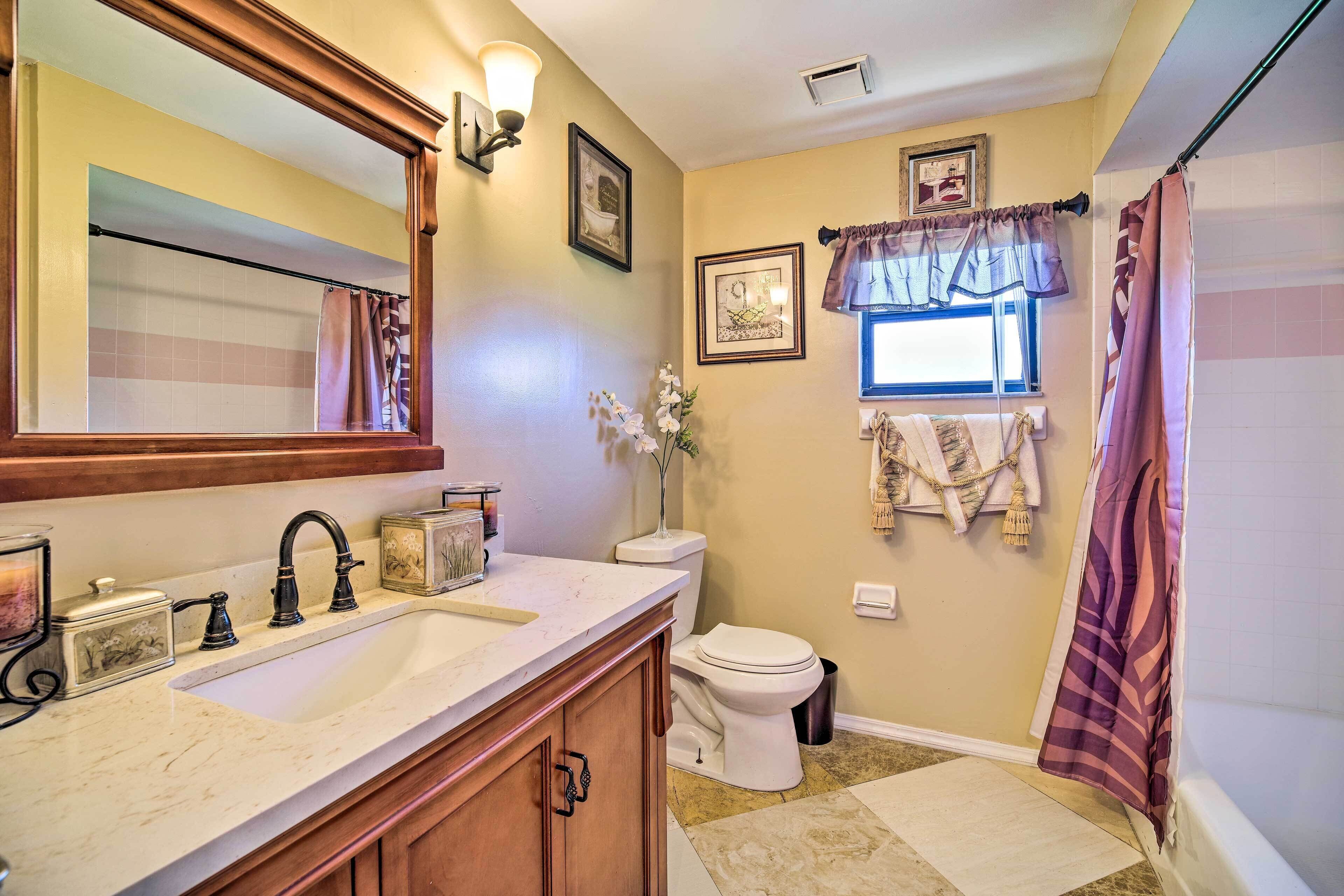 A bathroom with a sink, mirror, toilet, and shower curtain.