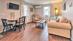A living room with a beige sofa, a coffee table, a TV mounted on the wall, and a chair.