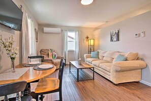 A living room with a sofa, coffee table, and dining area with chairs and a table.