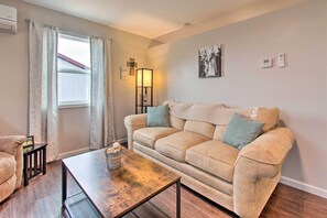 A living room with a beige sofa, a wooden coffee table, a lamp, and a window with curtains.