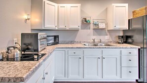 A modern kitchen with white cabinets, a granite countertop, a built-in stove, a microwave, and a stainless steel refrigerator.