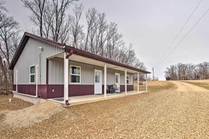 A single-story building with a covered porch and a gravel driveway. - Updated Missouri Cabin Rental on Large Farm (Canton)