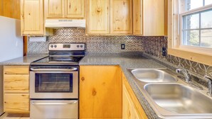 A kitchen with wooden cabinets, a stainless steel sink, and a window. - Pet-friendly Cabin With Designated Boat Slip! (Higden)