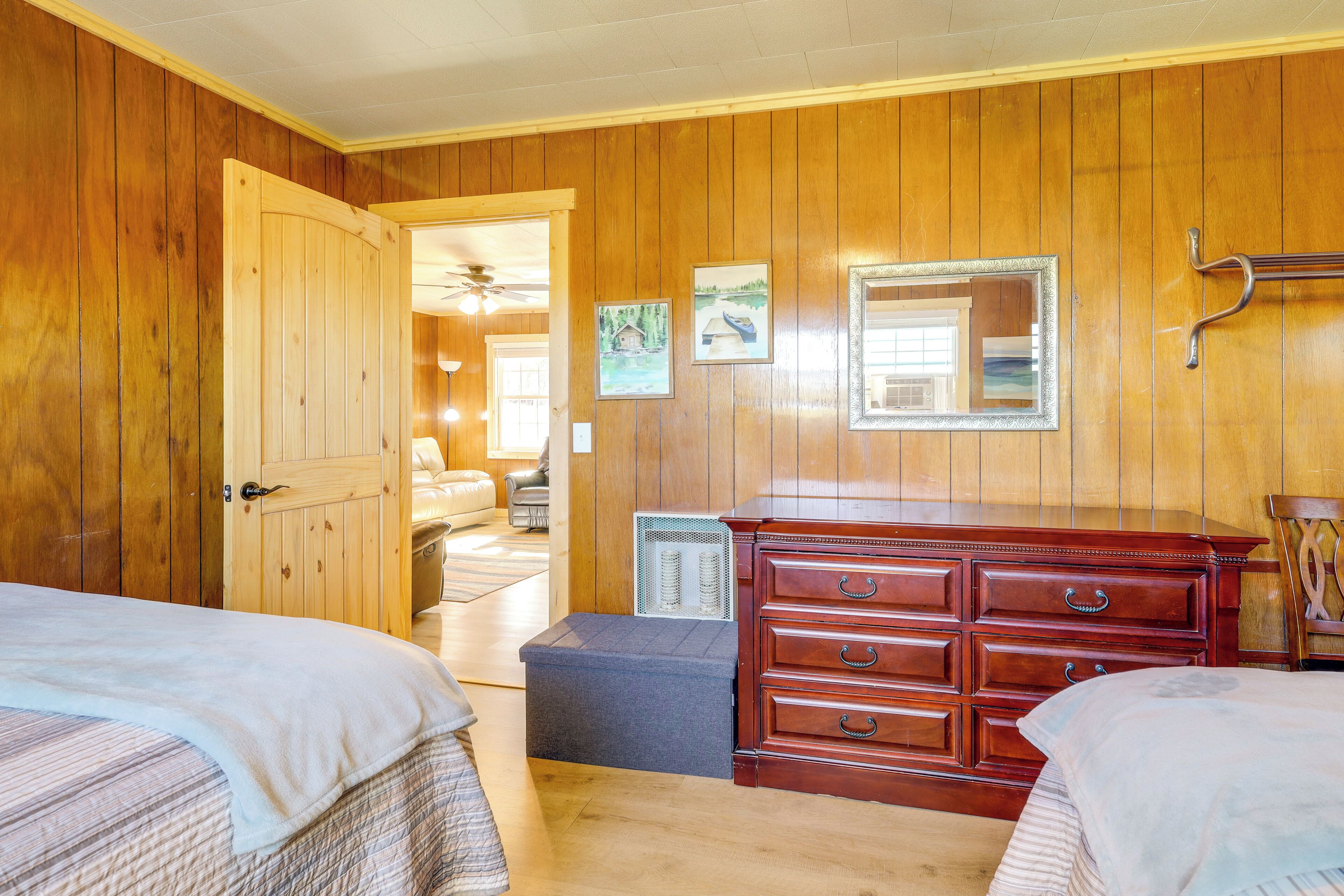 A room with wooden walls, a bed, a dresser, and a mirror.