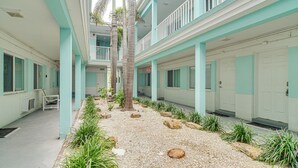 A hotel corridor with a central pathway, palm trees, and a gravel area. - Tropical Pass-a-grille Gem w/ Direct Beach Access! (St. Pete Beach)