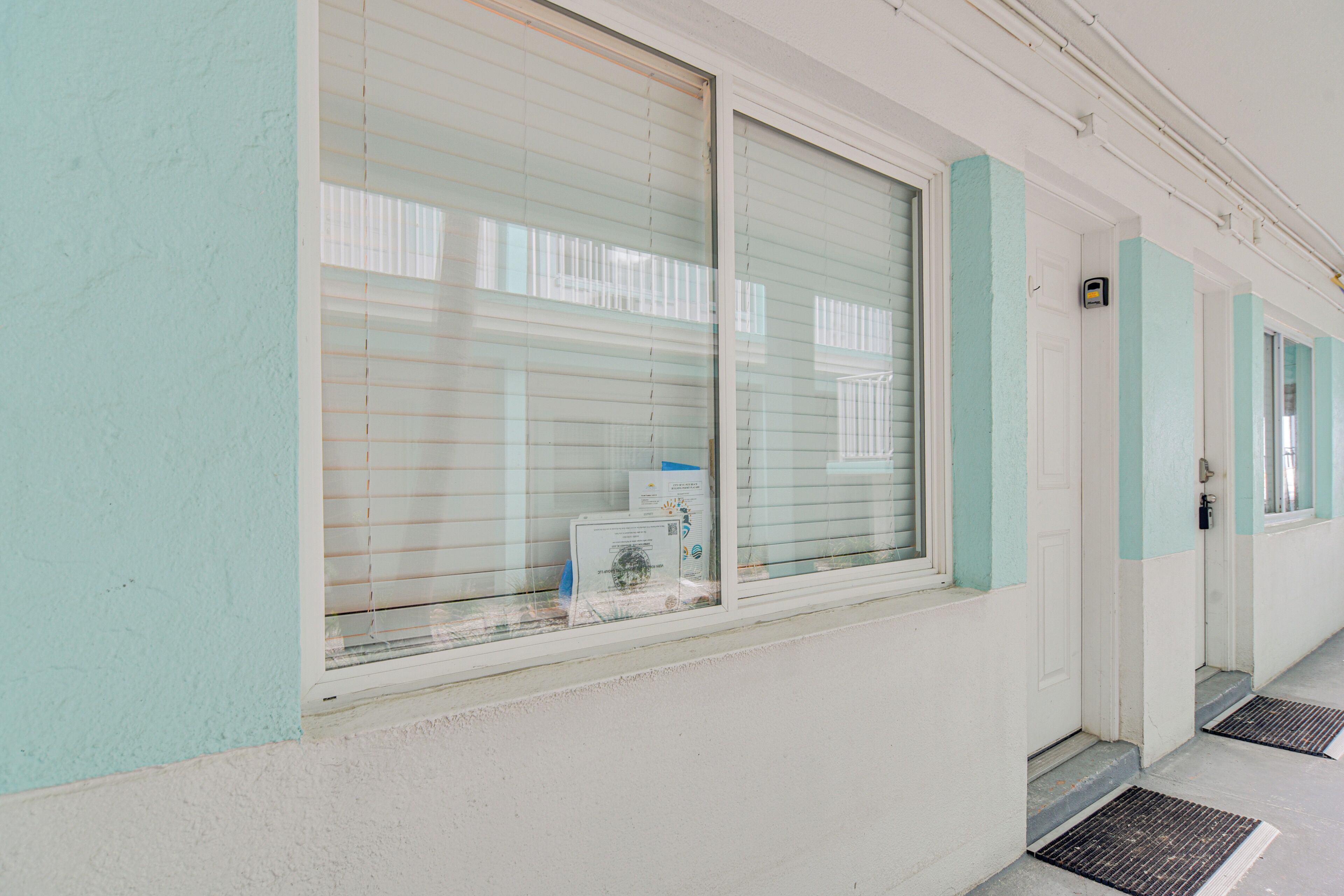 Un pasillo con una ventana, una puerta y un pequeño escalón que da a otra habitación.