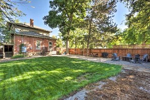 A backyard with a well-maintained lawn, a wooden deck, and a barbecue area.