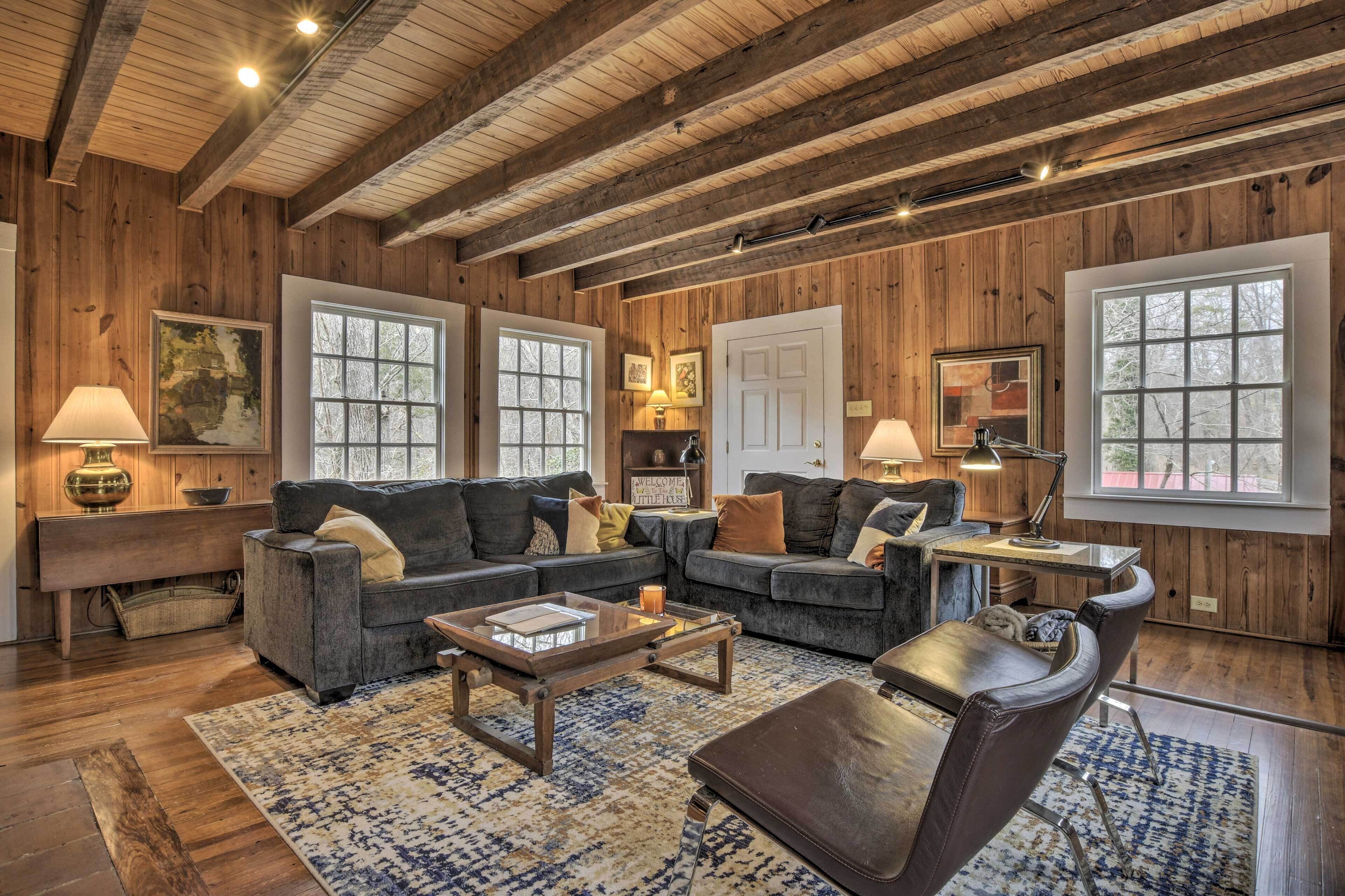 A cozy living room with wooden walls and ceiling, a sectional sofa, a coffee table, and a dining area with a table and chairs.