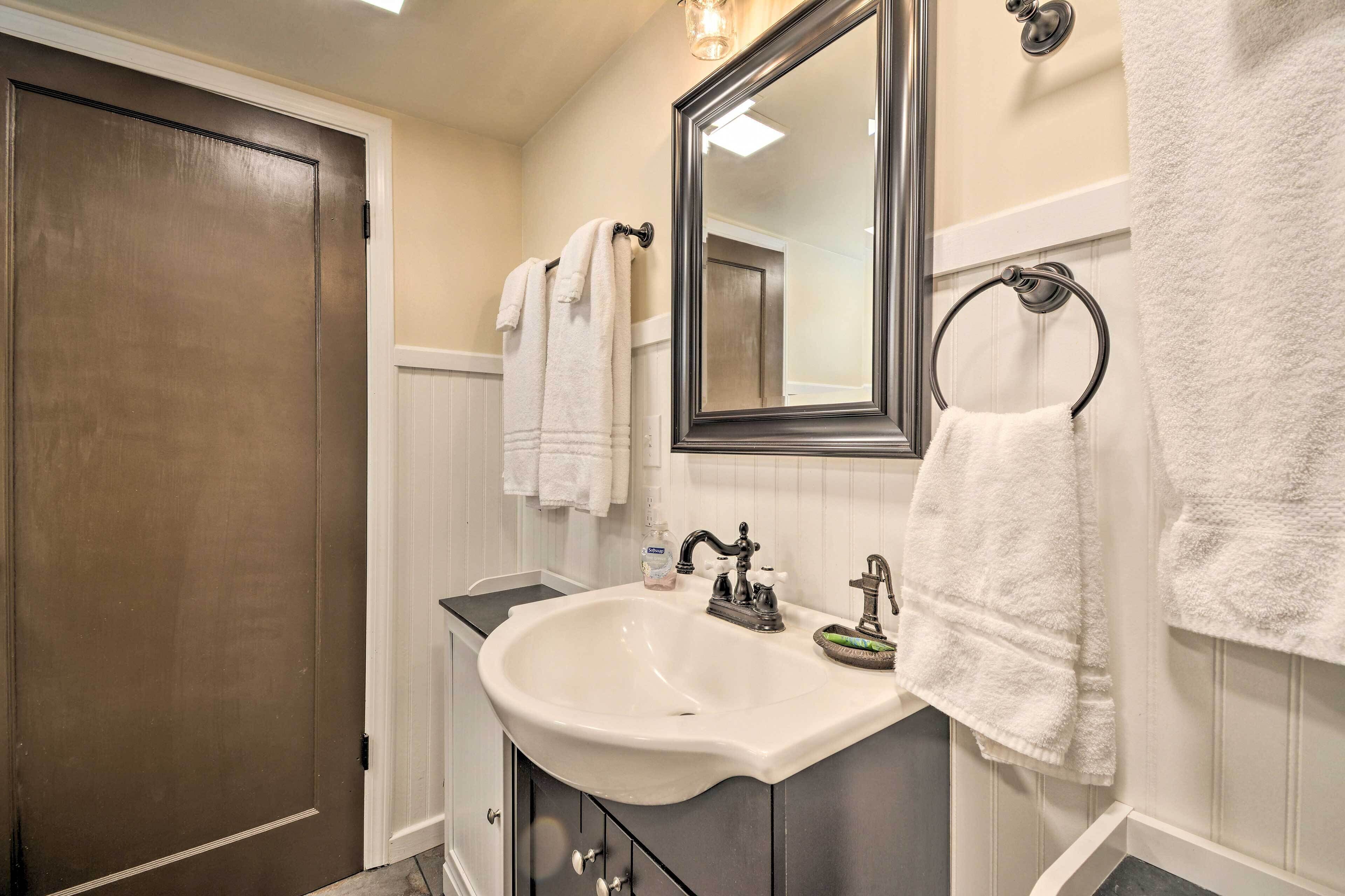 A bathroom with a white sink, dark cabinets, a large mirror, and white towels.