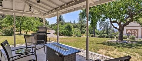 An outdoor patio with a grill, seating, and a view of the surrounding landscape.