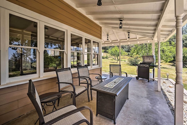An outdoor patio with a table and chairs, a grill, and a view of the surrounding landscape. - Historic Mariposa Stagecoach Stop w/ Gas Fire Pit! (Mariposa)