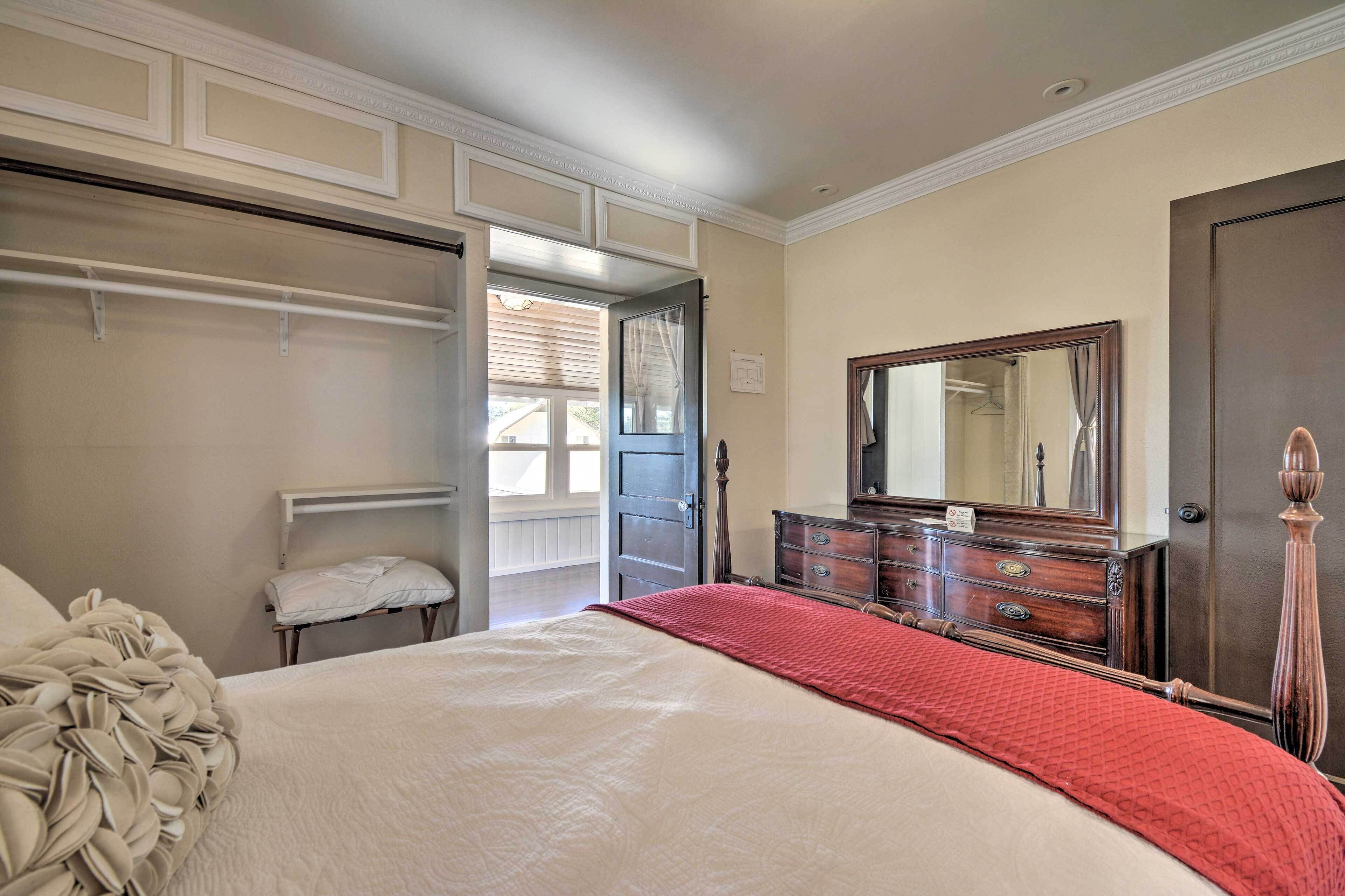 A bedroom with a bed, a dresser, a mirror, and a closet.