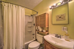A bathroom with a shower, toilet, sink, and a towel rack.