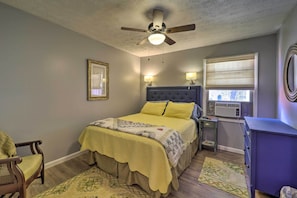 A bedroom with a bed, a ceiling fan, bedside lamps, a window with blinds, a dresser, and a chair. - Nature Escape in Wytheville w/ Covered Porch! (Speedwell)