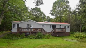 A two-story house with a red roof, wooden deck, and a staircase leading to the upper floor. - Life on the Lake With Private Dock & Fire Pit! (Winthrop)