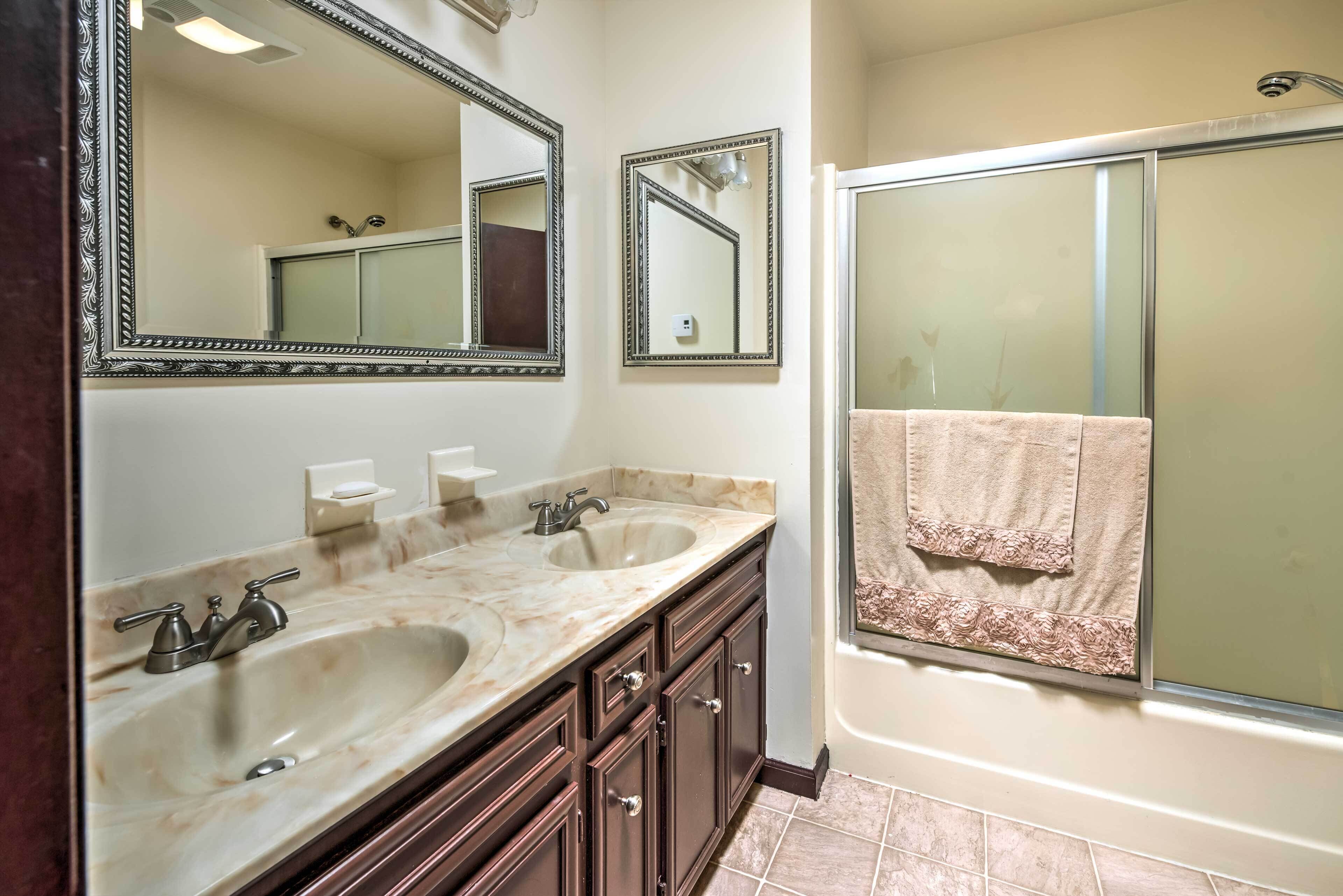 A bathroom with two sinks, a large mirror, and a glass-enclosed shower.