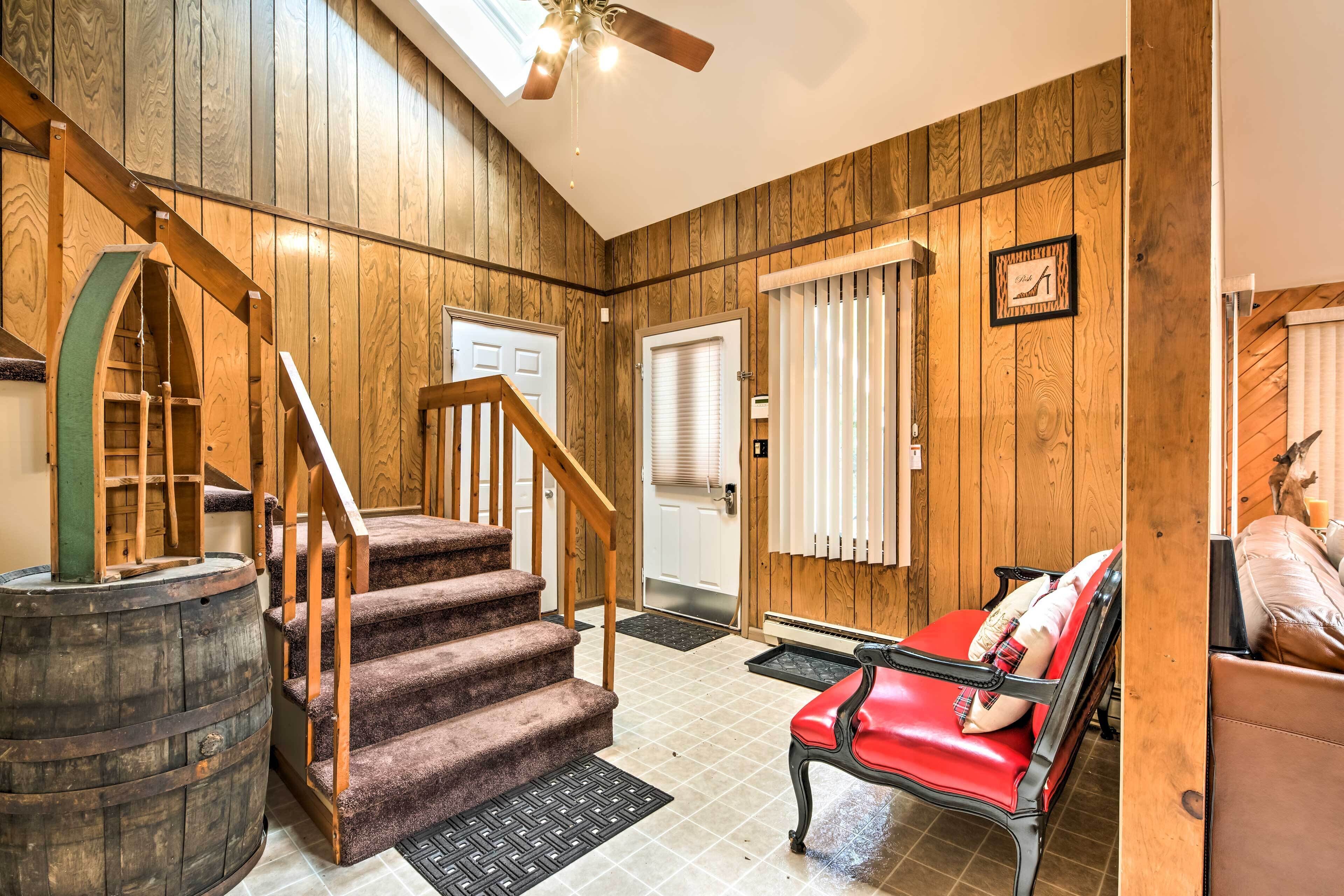 A wooden interior with a staircase, a red leather bench, and a door with a window.