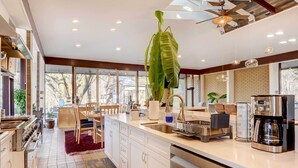 A modern kitchen with white cabinets, stainless steel appliances, and a large hanging plant. - Stylish + Serene West Friendship Hidden Gem! (West Friendship)