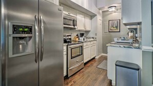 Uma cozinha moderna com eletrodomésticos de aço inoxidável, armários brancos e piso de madeira.