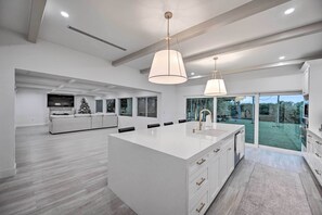 A spacious kitchen with a large island, white cabinetry, and pendant lighting. - Lakefront House: Hot Tub & Golf Course Views! (Marco Island)