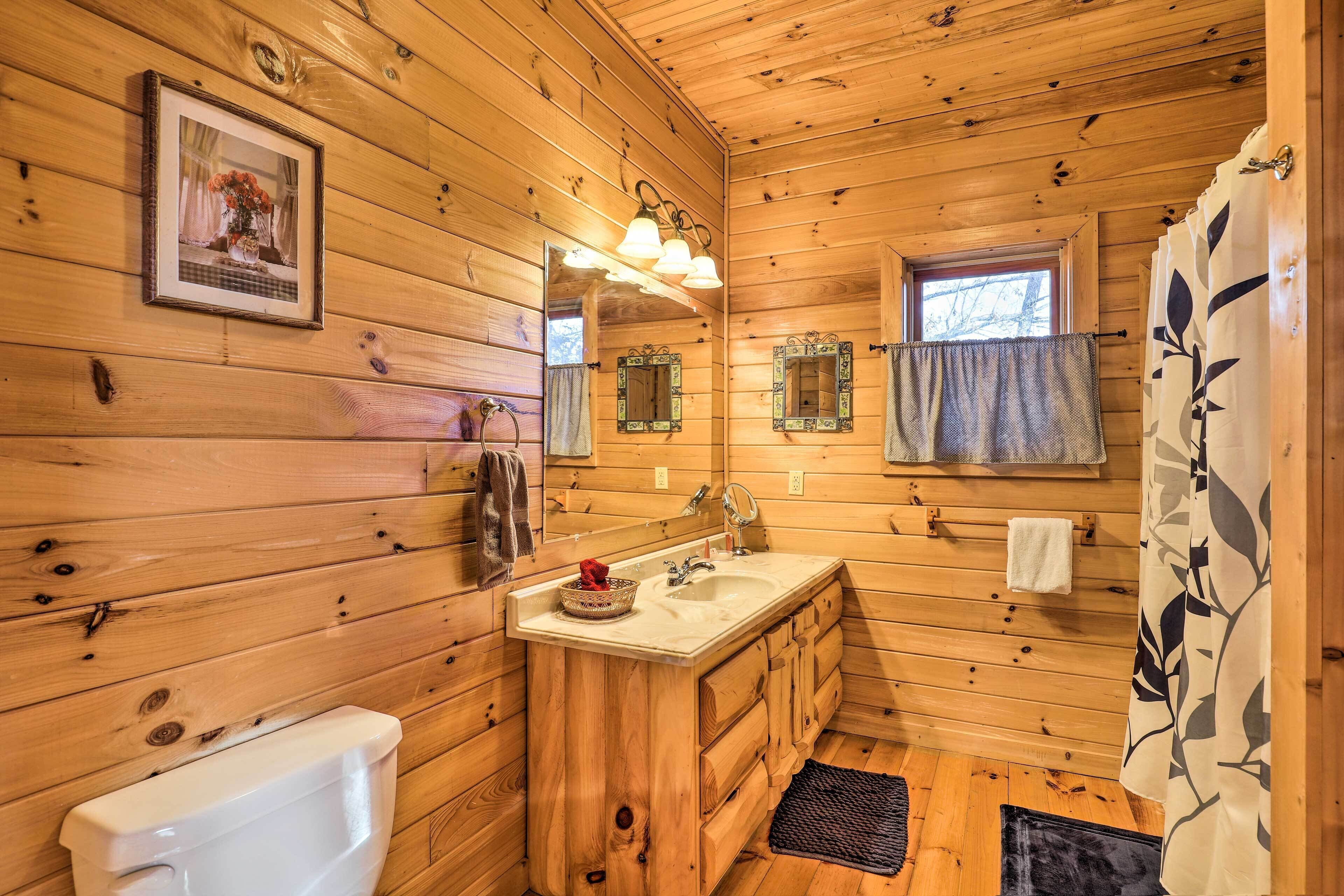 A wooden cabin bathroom with a toilet, sink, and mirror.