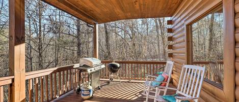A wooden deck with a grill, a fan, and rocking chairs.