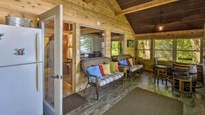 L'intérieur d'un chalet en bois comprend un coin repas, un canapé et un réfrigérateur.