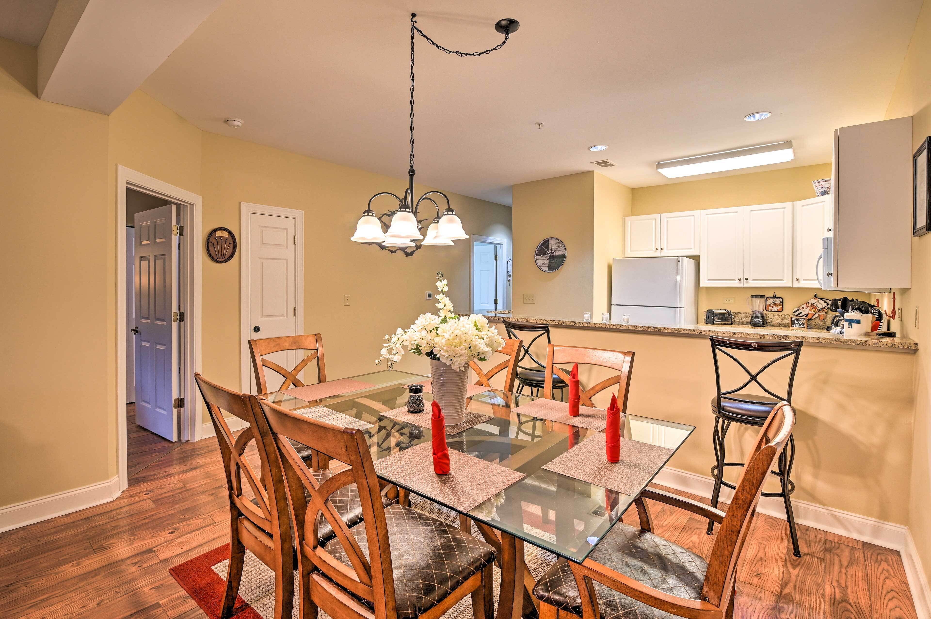 A dining area with a glass table, wooden chairs, and a chandelier.