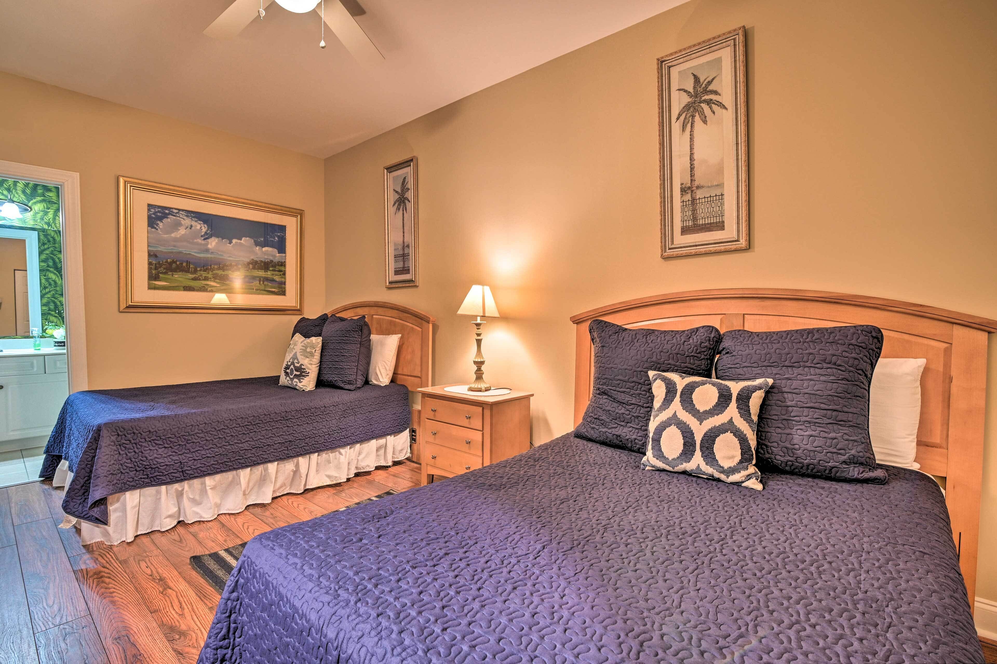 A hotel room with two beds, a nightstand with a lamp, and framed pictures on the walls.