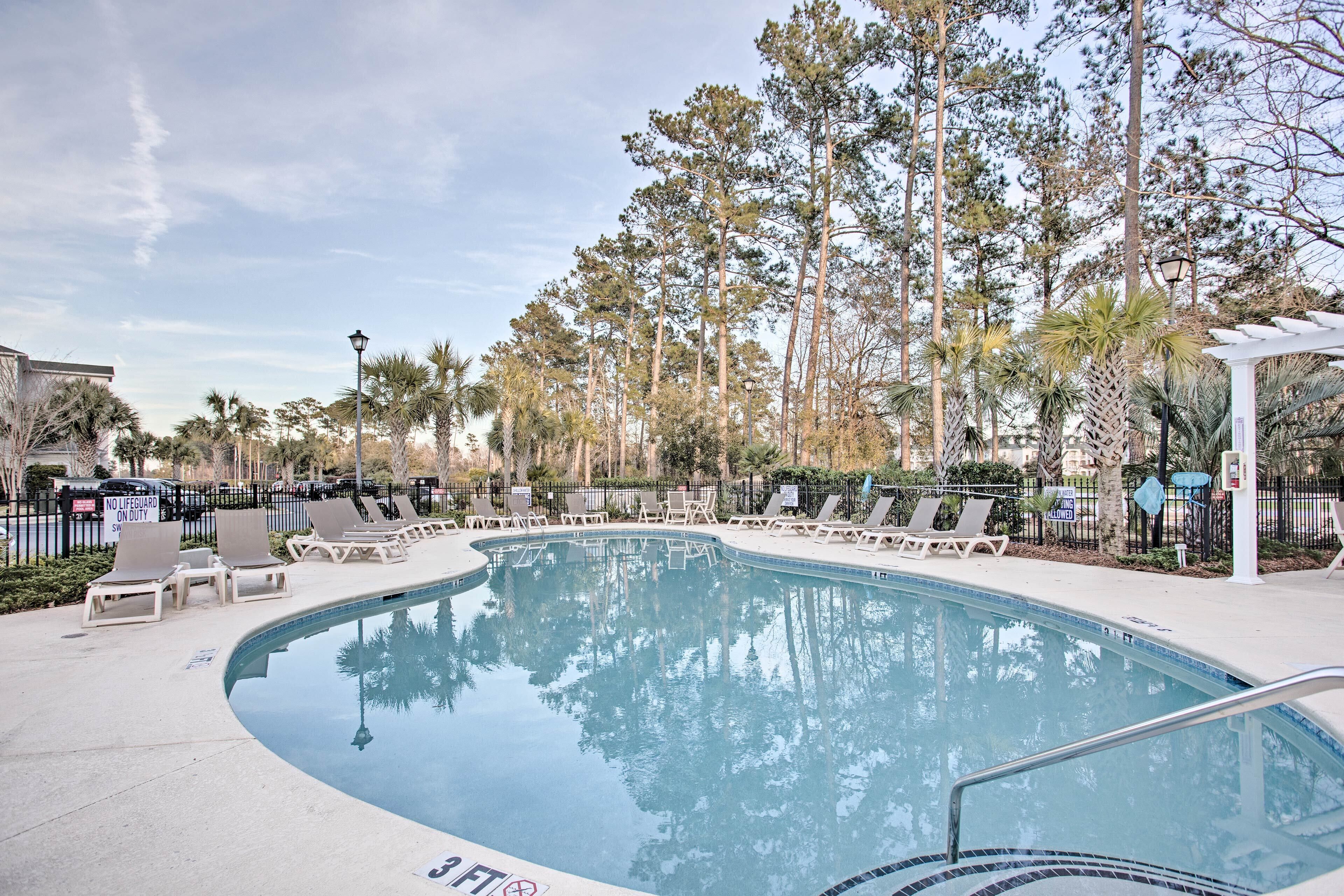 A pool area with lounge chairs and a no lifeguard on duty sign.