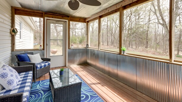 A covered porch with a ceiling fan, wicker furniture, and a view of the surrounding trees. - Pittsburg Vacation Rental < 1 Mi to Boat Launch (Pittsburg)