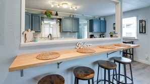 A kitchen with a wooden bar area, blue cabinets, and a large mirror. - Pittsburg Vacation Rental < 1 Mi to Boat Launch (Pittsburg)