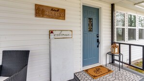 A porch with a blue door, a welcome sign, and a sign indicating 'Hattell Hideaway'. - Pittsburg Vacation Rental < 1 Mi to Boat Launch (Pittsburg)