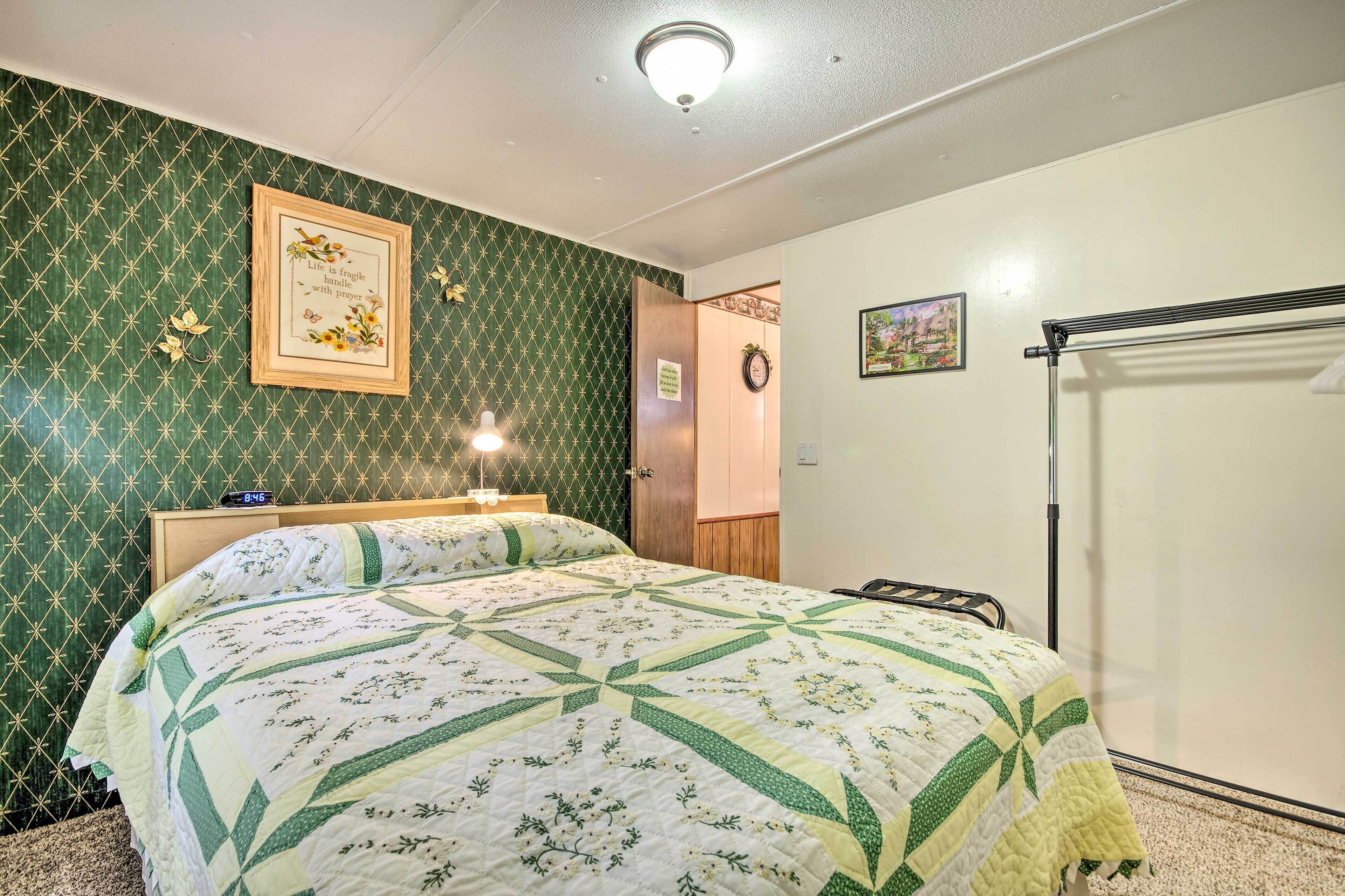 Un dormitorio con una cama, una mesita de noche, un reloj de pared y una puerta.