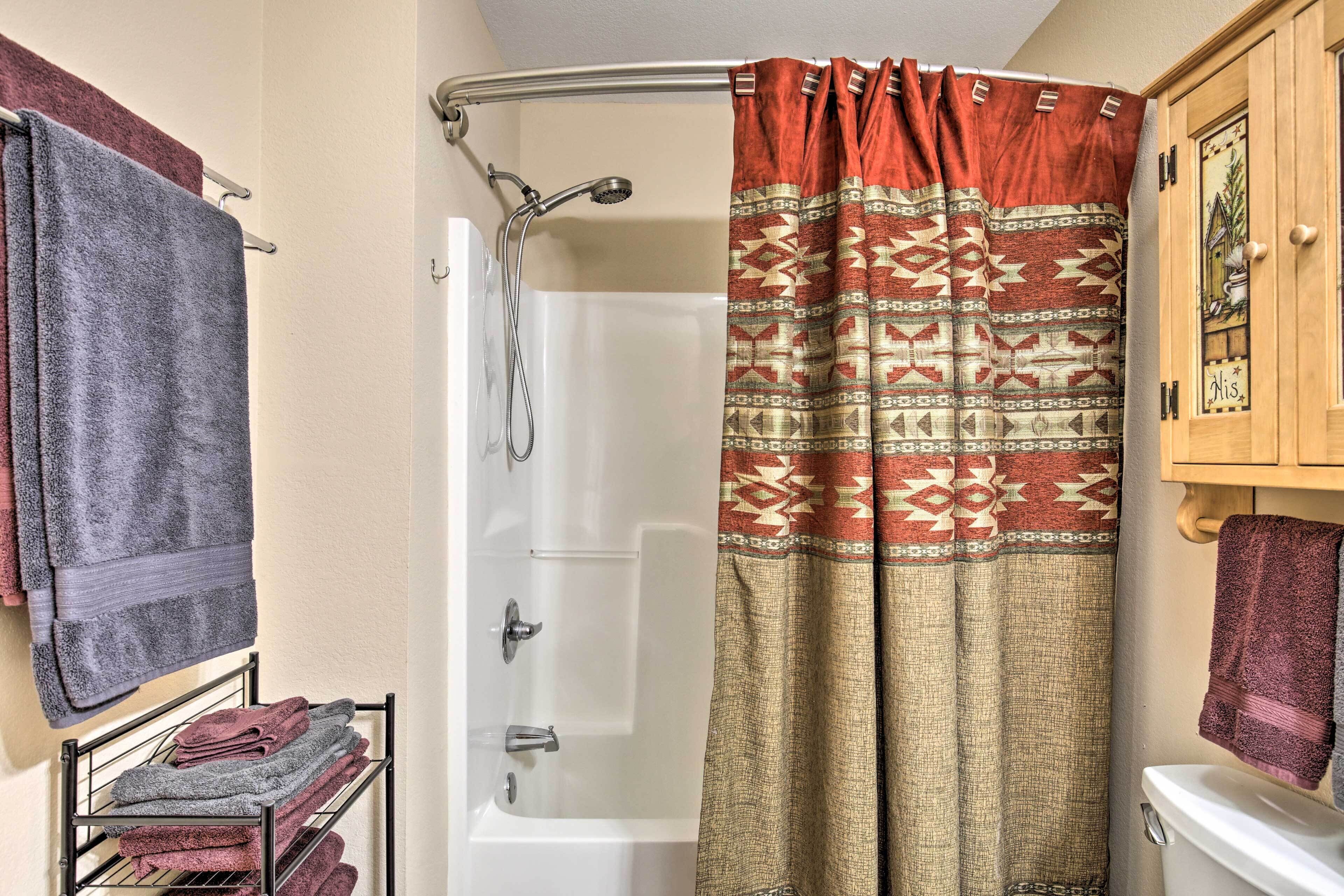 A bathroom with a shower curtain, a toilet, and a towel rack with towels.