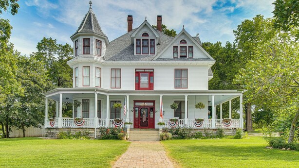 A large, two-story house with a wrap-around porch and a tower on the left. - Creekfront Yellville Manor w/ Parlors & Fire Pit! (Yellville)